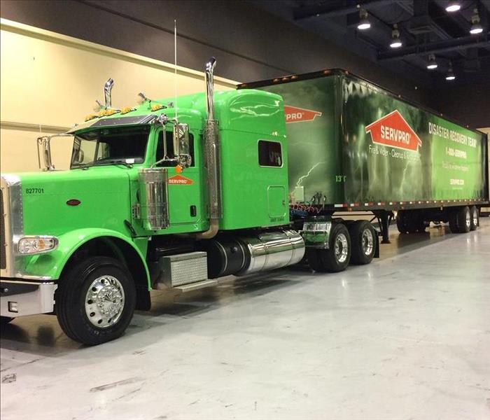 Green 18-wheeler truck with servpro trailer attached to it in warehouse like building