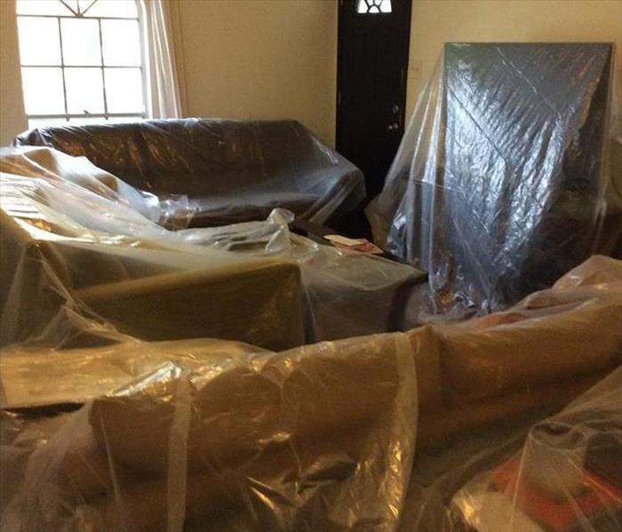 Furniture covered in protective plastic in a home.