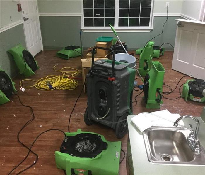 room with green SERVPRO equipment all over, sink in bottom right corner, window on back wall